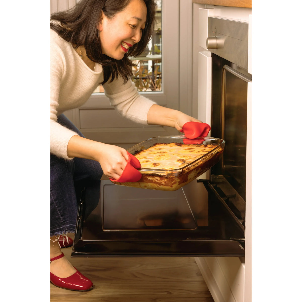 Chef using O'Cuisine Large Roasting Dish, demonstrating easy handling with oven mitts while serving a delicious meal.