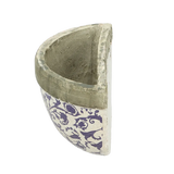 The aged ceramic wall planter in a garden setting, showcasing how it enhances outdoor spaces.