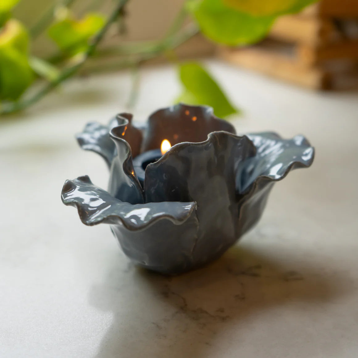 The Flower Shaped Tealight Holder - Blue surrounded by soft light, emphasizing its function as a lovely flower tealight holder.