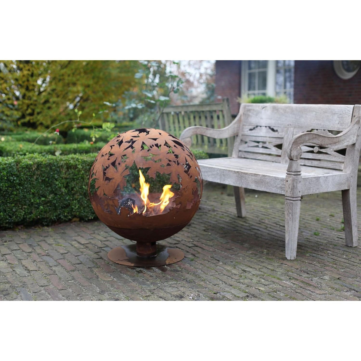 Outdoor setting with the rust fire ball featuring laser cut leaves; a stylish laser cut fire pit for your backyard.