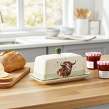 Butter dish with a cow design on a kitchen counter with bread and jam