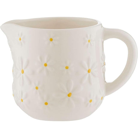 A white ceramic milk jug with embossed yellow daisy designs and a hand-painted yellow center.