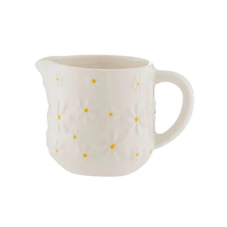 White ceramic pitcher with yellow polka dots on a white background