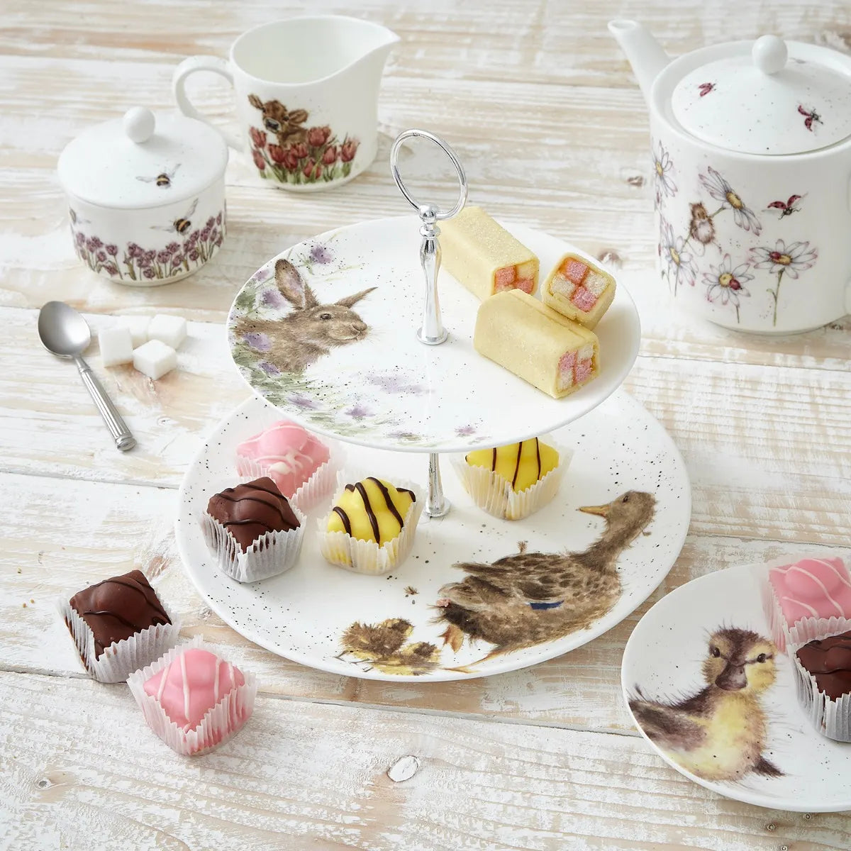 Royal Worcester Wrendale Designs two-tier cake stand set up for a tea party, highlighting its exquisite porcelain craftsmanship.
