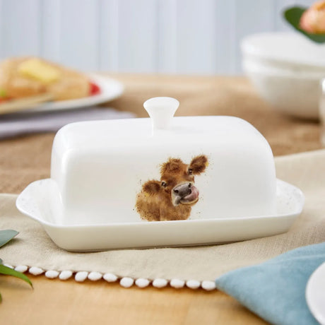 Royal Worcester Wrendale Covered Butter Dish beautifully styled on a dining table, showcasing its elegant cow design. This Wrendale Designs butter dish is perfect for serving and adds charm to any meal.