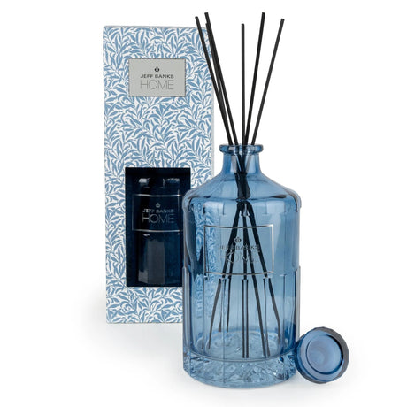 Jeff Banks Home reed diffuser set featuring a translucent blue glass bottle with black reeds, shown next to its blue and white patterned packaging box and a small matching blue cap on a white background.