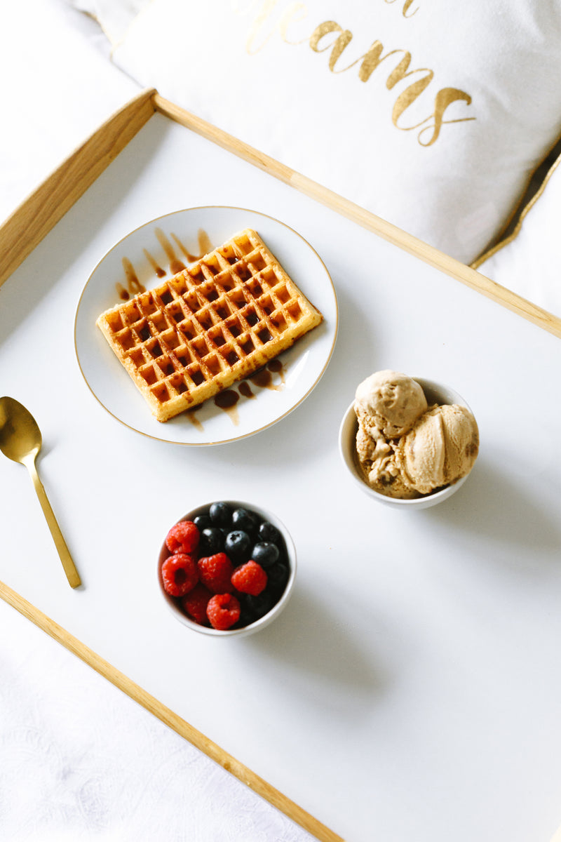 White and wood breakfast-in-bed tray with waffle, ice cream and berries